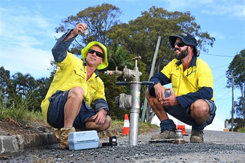 Two council workers in high viz testing water.