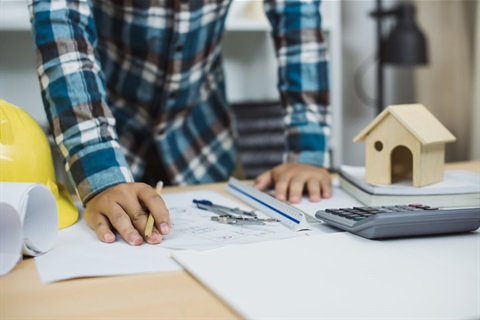 Man leaning over property plans on desk