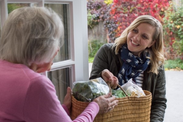 Lady brings elderly neighbour some groceries.