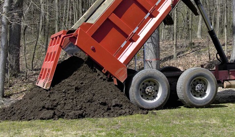 Truck dumping dirt onto ground