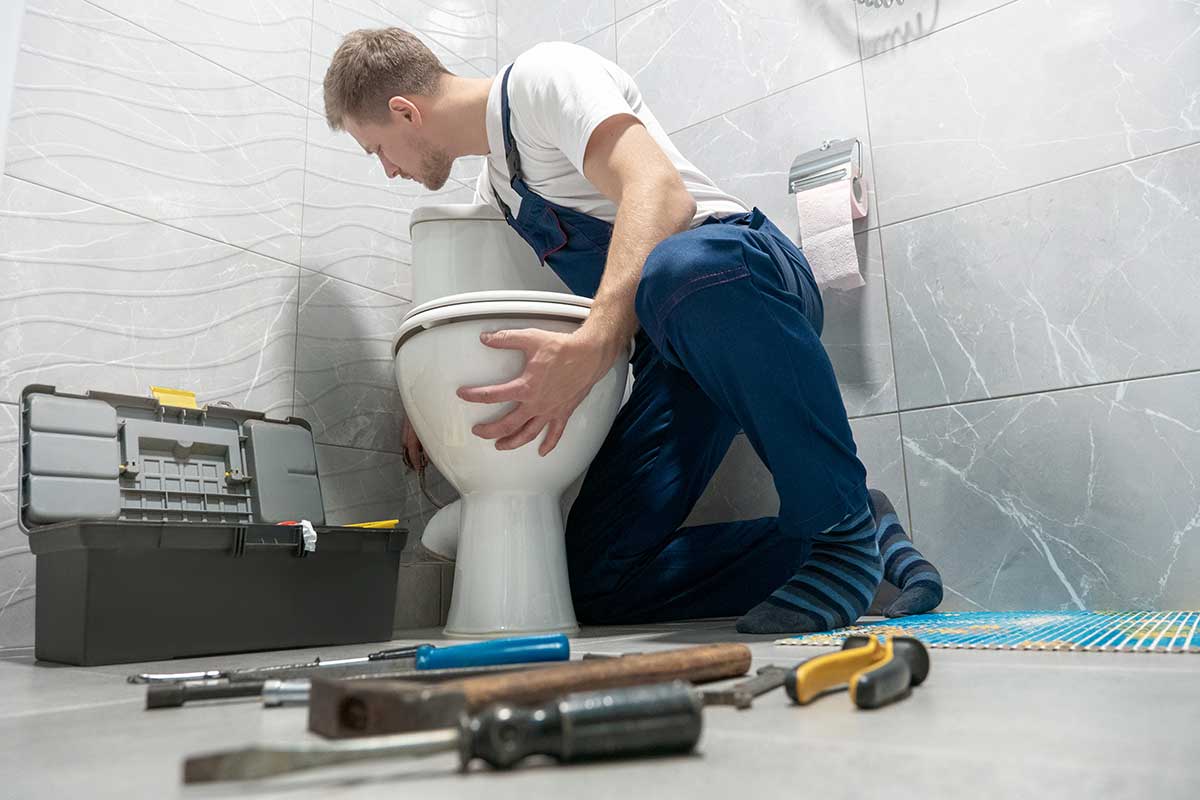 Plumber fixing toilet leak